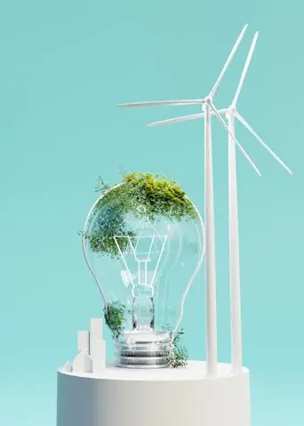 A light bulb holding a small forest, next to wind turbines.