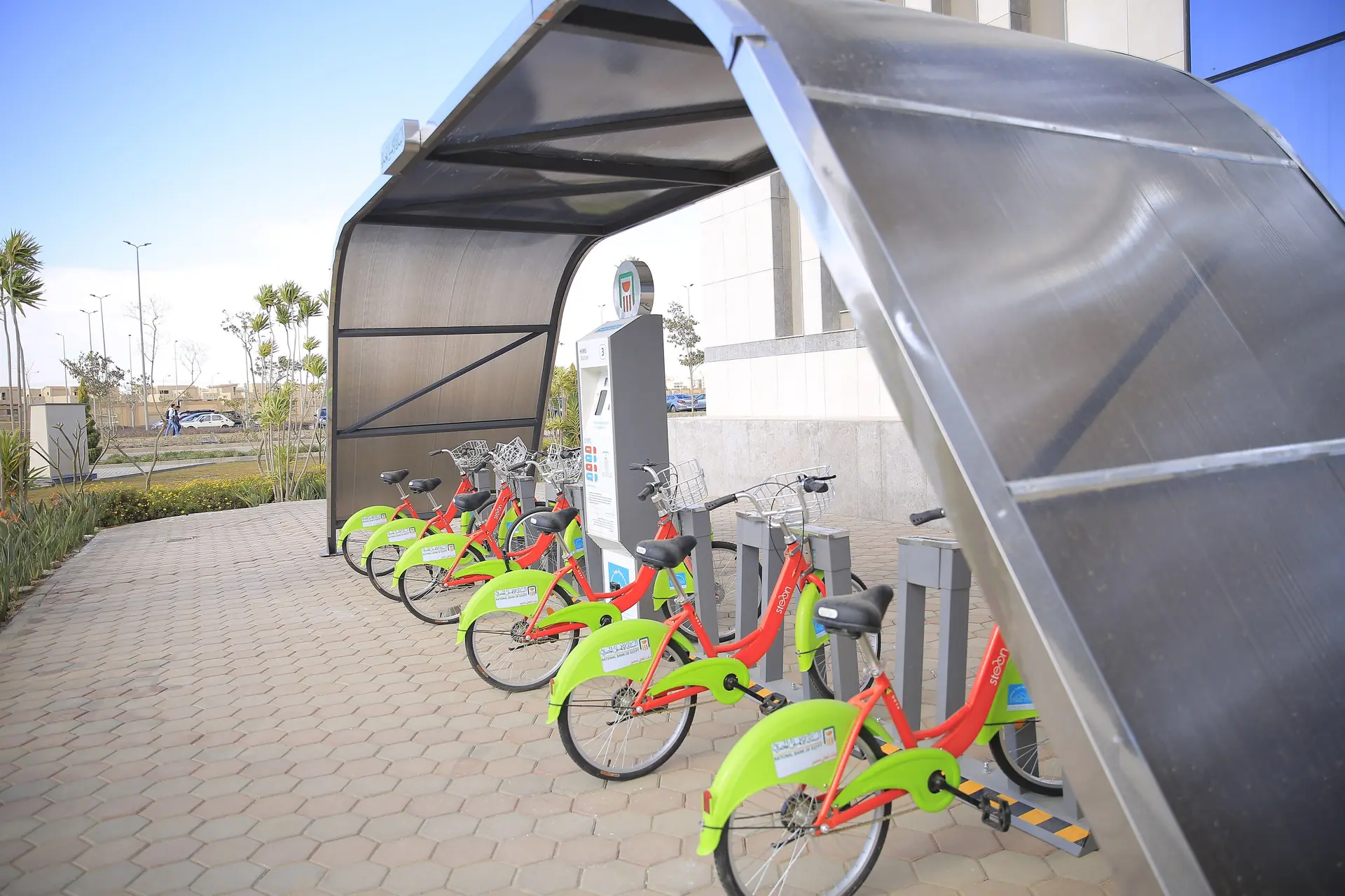 Lime-green shared bicycles parked under a curved shelter on campus.
